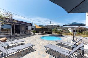 A pool area with lounge chairs, a pool, and umbrellas.