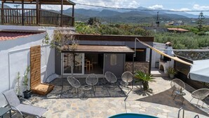 A patio with stone flooring, outdoor seating, and a pool. - Three Waves Maisonettes Elena (Agios Nikolaos)