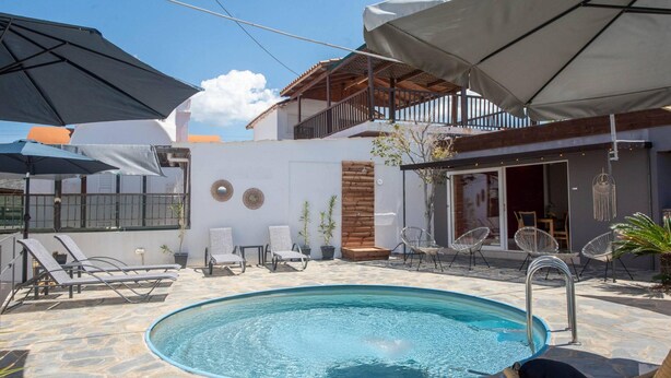 A pool area with lounge chairs, umbrellas, and a wooden deck. - Three Waves Maisonettes Elena (Agios Nikolaos)