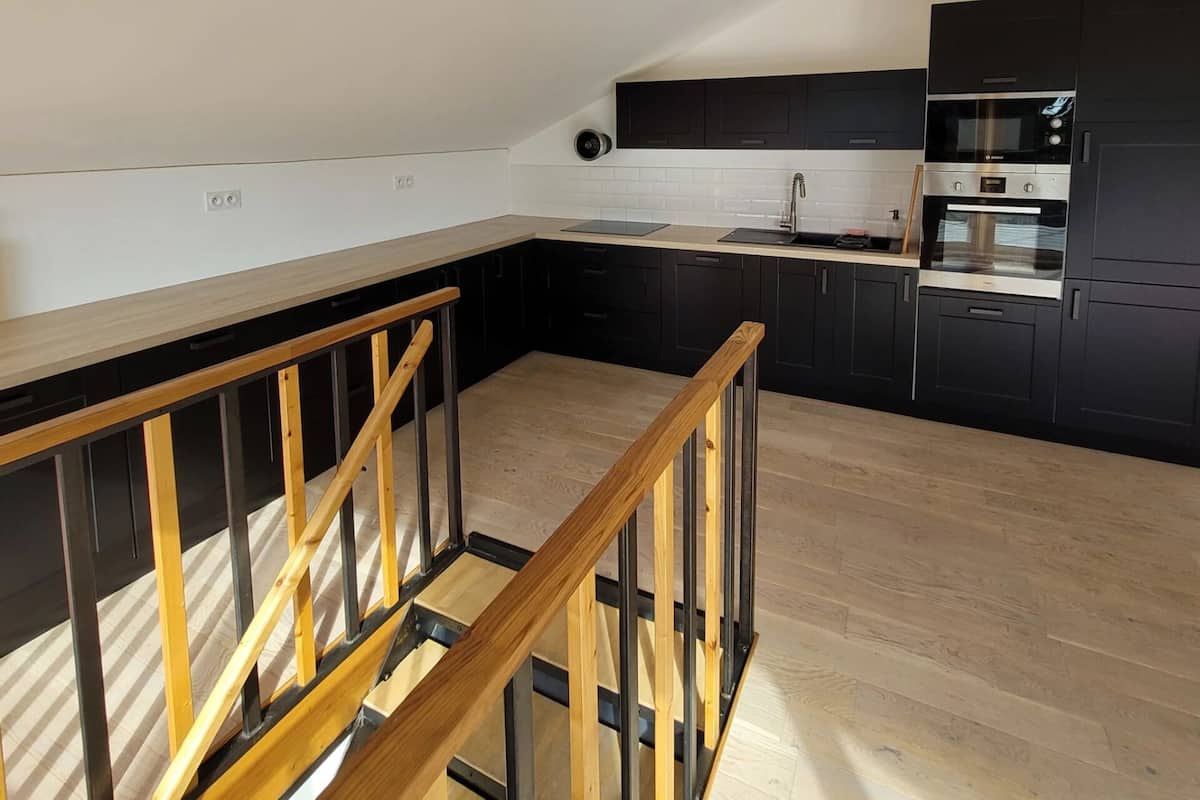 A modern kitchen with black cabinets, a wooden countertop, and a built-in oven.