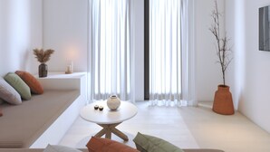 A modern living room with a sofa, a coffee table, and a potted plant. - 2-bedroom Villa Kalypso (Antiparos)