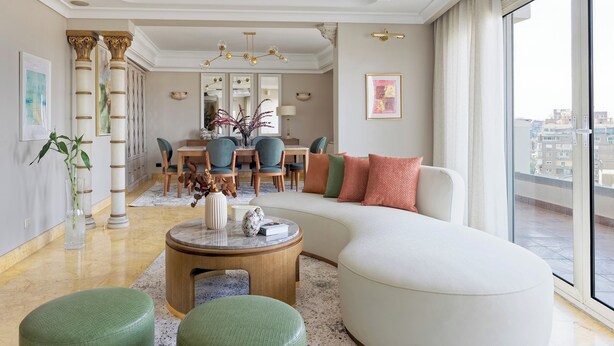 Un salon moderne avec un canapé aux lignes courbes, une table basse ronde et un coin repas comprenant des chaises et une table.