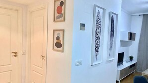Una habitación con una puerta, una pared blanca y una estantería con una planta.