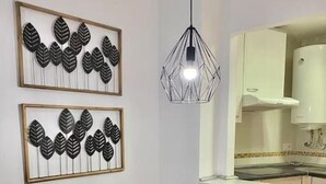 Un comedor con una mesa de vidrio, sillas negras, una lámpara colgante y dos decoraciones en la pared con motivos de hojas.