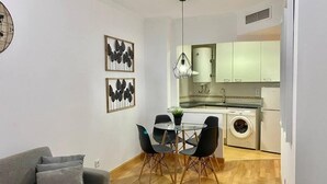 Un espacio habitable compacto con zona de comedor, sofá, cocina equipada con lavadora y ventilador de techo.