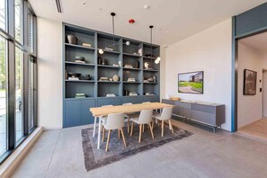 A modern interior with a dining area, built-in shelving, and a large window. - Landing | Spectacular 2BD, Rooftop Lounge, Gym (Durham)