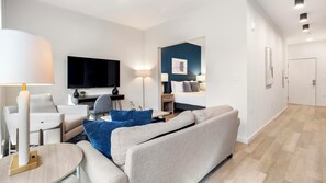A modern living room with a flat-screen TV, a sofa, a coffee table, and a lamp.