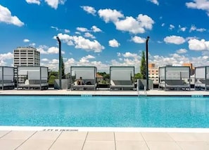 A swimming pool with lounge chairs and a clear sky.
