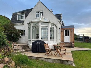 Enjoy outdoor cooking in the conservatory with a barbecue grill, surrounded by a grassy area and a stone pathway.