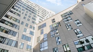 Ein mehrgeschossiges Gebäude mit modernem architektonischen Design, das große Fenster und eine rasterartige Fassade aufweist.