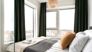 Ein Hotelzimmer mit Bett, Blick auf die Stadt und einem Vorhangfenster.