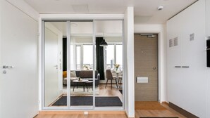Ein modernes Interieur mit einer Schiebetür aus Glas, die zu einem Wohnbereich führt, Holzboden und einem schwarzen Teppich.