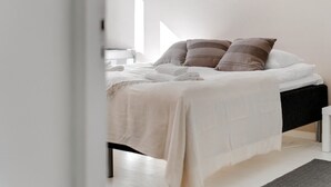 Una cama bien hecha con una colcha blanca y beige, dos almohadas y un cabecero negro.