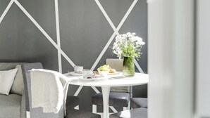Una habitación moderna con una mesa blanca, un sofá gris y un diseño geométrico en la pared.