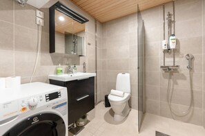 A modern bathroom with a washing machine, a toilet, a sink, and a shower. - Superior Queen Room in Tammela Soccer Stadium! (Tampere)