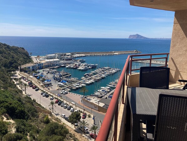 A balcony with a view of a marina, boats, and a distant mountain.