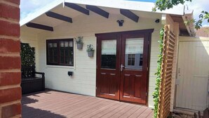 Een huis met een houten terras, een voordeur en een kleine tuin.