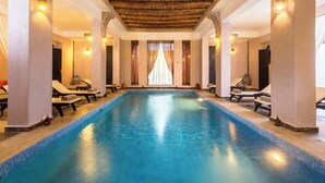 A large indoor swimming pool with lounge chairs and a wooden ceiling. - Hapimag Resort Marrakesh (Marrakech)