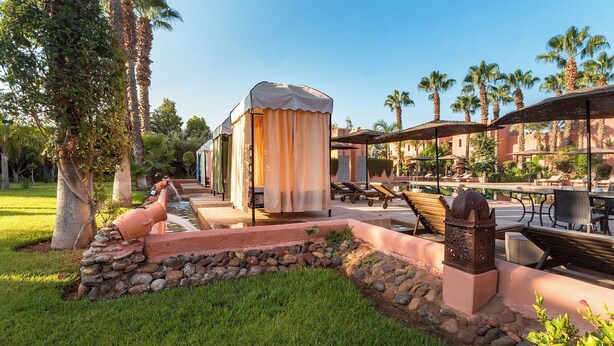 A poolside area with lounge chairs, a covered seating area, and a water feature. - Hapimag Resort Marrakesh (Marrakech)