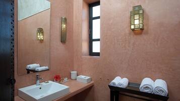 Un baño con lavamanos, espejo, toallero y apliques decorativos.
