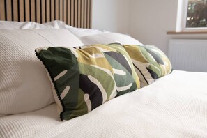 A bed with white bedding and two decorative pillows with a camouflage pattern. - Dorset Stylish Apartment (Poole)