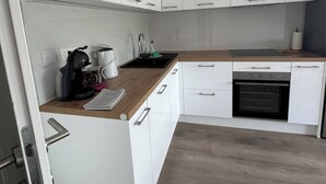 Una cucina moderna con mobili bianchi, un piano di lavoro in legno, una macchina da caffè e un forno integrato.