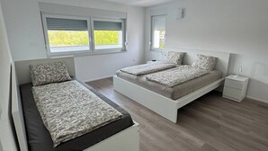 Una camera da letto moderna con due letti, un comodino e una finestra con persiane.