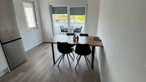 Una cucina moderna con tavolo e sedie in legno, un frigorifero e vista all'esterno attraverso una finestra.