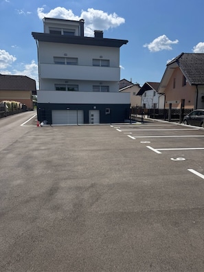A multi-story building with a garage door, parking spaces, and a clear sky.