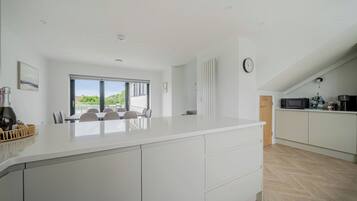 A modern kitchen with a large island, a dining area with a view, and a clock on the wall.