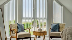 A room with two chairs, a round table, and a view through large windows. - Seaddler (Holyhead)