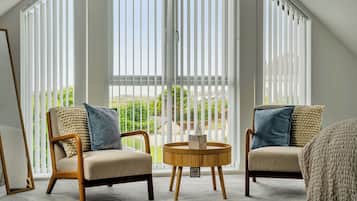 A room with two chairs, a round table, and a view through large windows.
