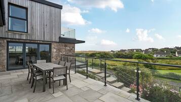 A modern house with a patio, stone walls, and a view of the countryside.