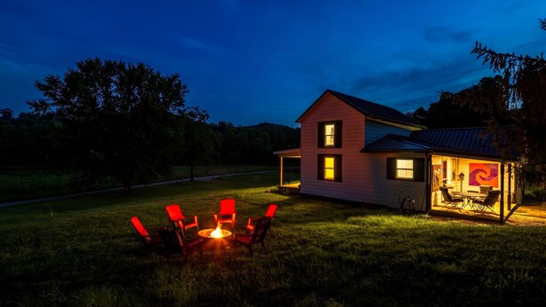A house with a fire pit and chairs in the yard, a covered outdoor area with a table and chairs, and a visible window. - Nature-Quiet Retreat • Firepit + BBQ • PetFriendly (McArthur)