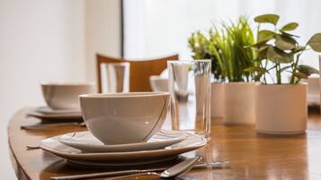 A dining table with a white bowl and plate set, a glass, and a potted plant.