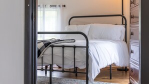 A bed with a metal frame, white bedding, a bedside table, and a dresser with drawers. - Nature-Quiet Retreat • Firepit + BBQ • PetFriendly (McArthur)