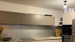 Eine moderne Küche mit hellen Schränken, einer Holzarbeitsplatte, einem Einbauofen und einem Spülbecken.