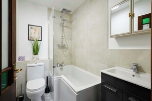 A bathroom with a toilet, shower, bathtub, sink, and a mirror.