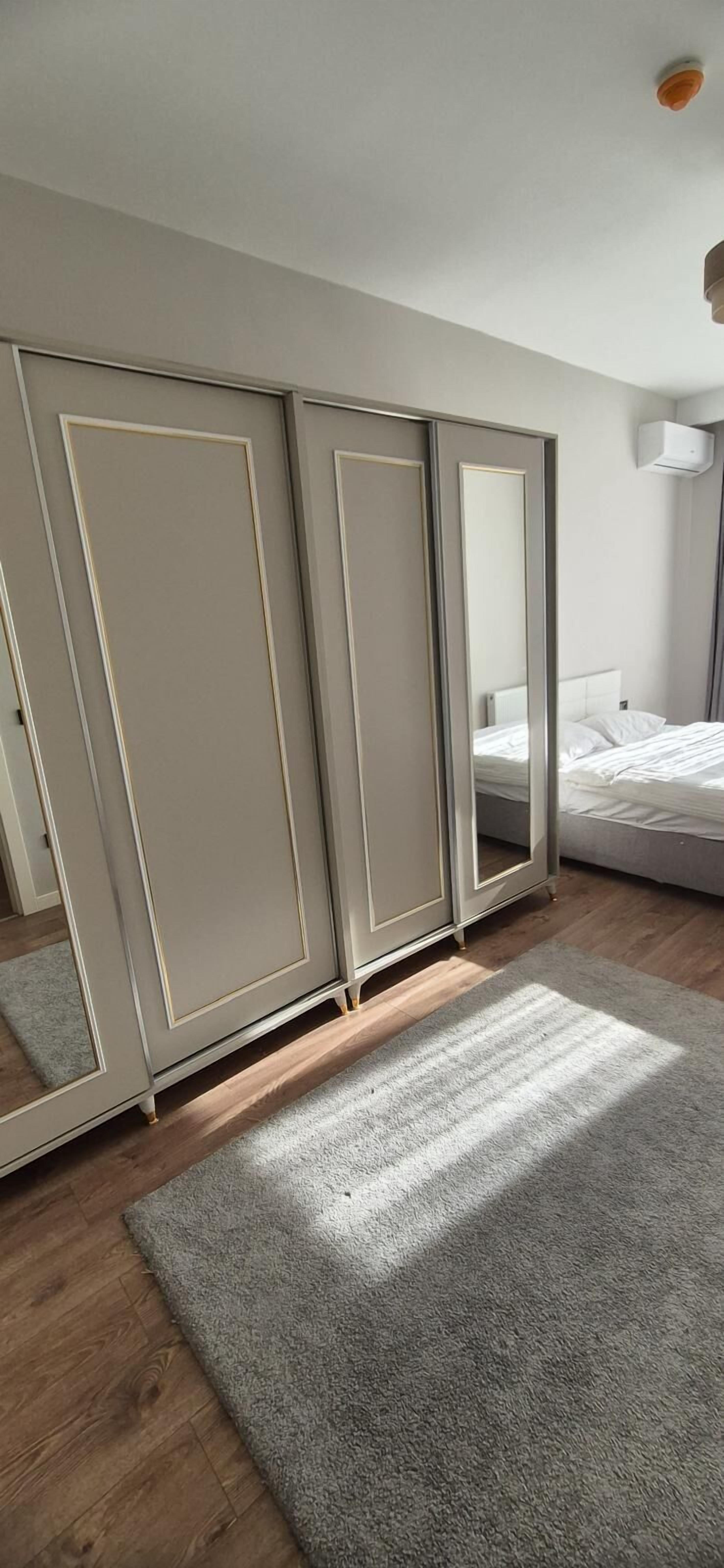 Une chambre avec une grande armoire, un lit et un luminaire au plafond.
