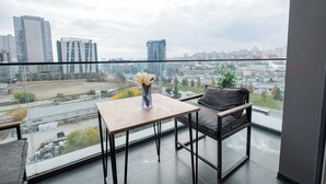 A balcony with a table and chair, a vase with flowers, and a city view. - LUX RESIDENCE 2 ROOMS 1 SALOON (Istanbul)