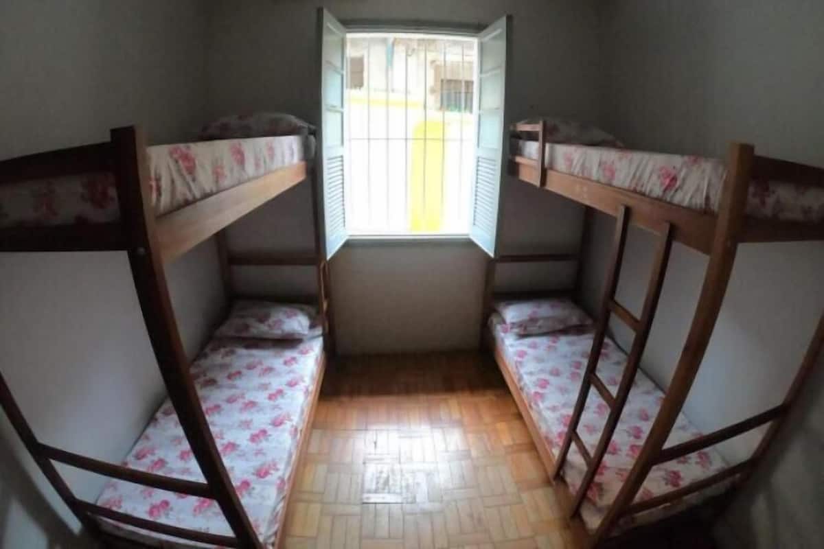 Quarto com beliches e janela com grades.