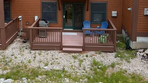 A two-story building with a balcony, a covered porch, and a gravel driveway. - Cozy Lake Region Townhome – Steps from Moose Pond in Bridgton (Bridgton)