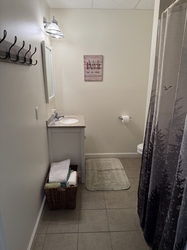 Un baño pequeño con lavabo, espejo, toallero y un cartel que dice "eat-ski-sleep-repeat".