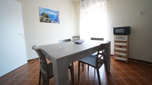 Un coin repas avec une table, des chaises, un saladier et un téléviseur posé sur un meuble.