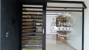 L’entrée d’un hôtel avec une porte coulissante en verre et une enseigne indiquant : « HOSPEDAGE Mi Fortaleza CALI 2024 Tequendama ».
