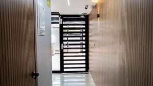 Un couloir moderne avec un sol brillant, des lambris en bois sur les murs et une porte à cadre noir au fond.