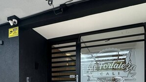 Une entrée moderne avec une porte en verre, une caméra de surveillance et un panneau indiquant le système d’alarme incendie.