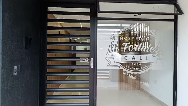 Entrada de un hotel con puerta corredera de vidrio, un letrero que dice "HOSPEDAGE Mt Fortez CALI 2024 TEQUENDA MA".