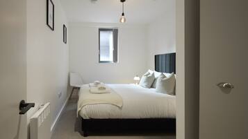 A bedroom with a bed, bedside lamp, and a window.