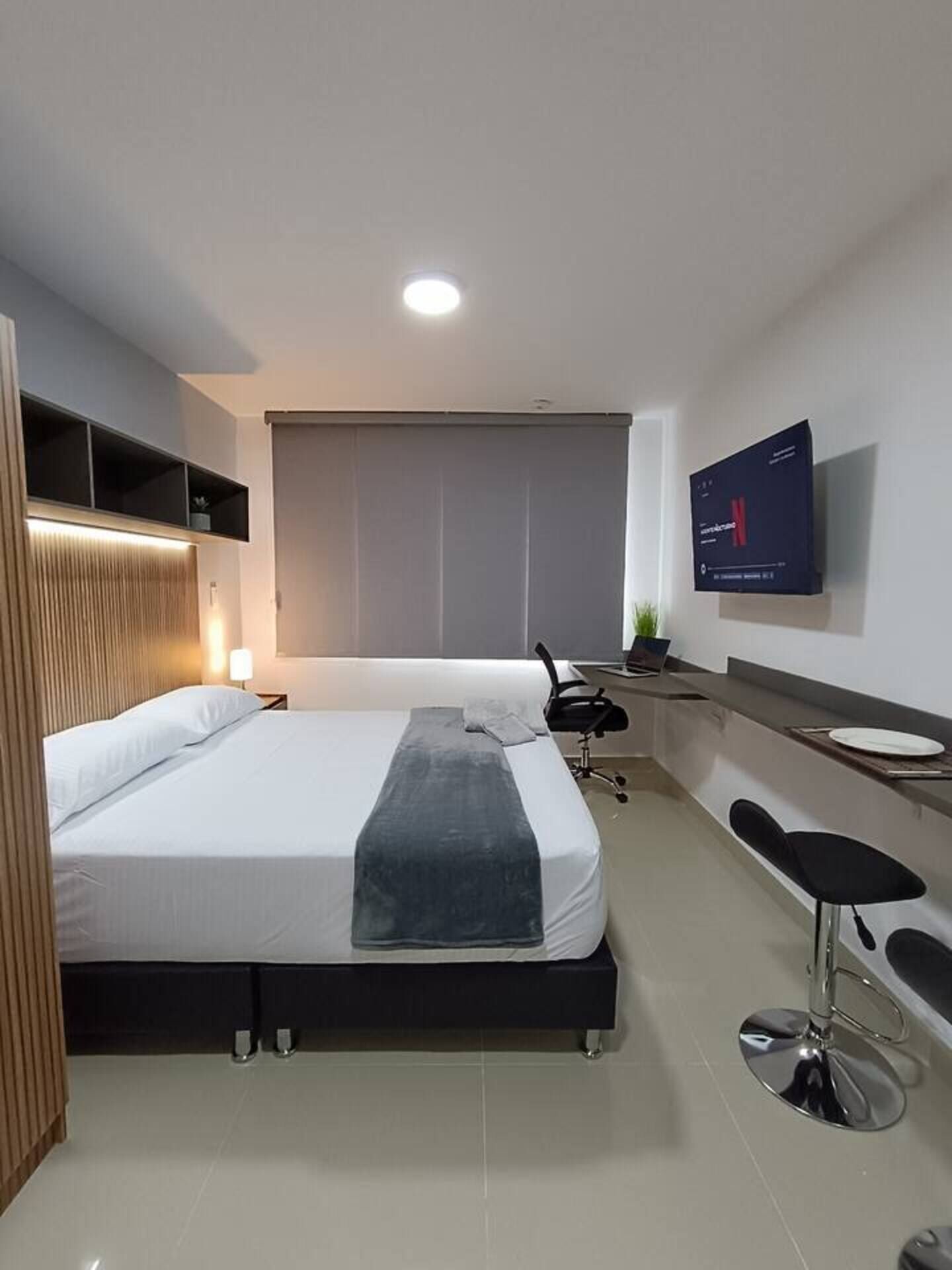Et moderne hotelværelse med seng, skrivebord, stol, fjernsyn og et vindue.